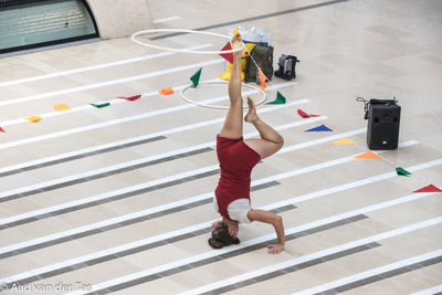 838379 Afbeelding van een meisje dat een gymnastische oefening met hoepels doet in een van de passages van Hoog ...